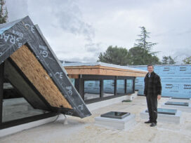 Owner Bryan Mekechuk stands proudly on his new roof which consists of Insulspan SIPs covered with a cool roof material--a 60 mil TPO membrane.  The gabled roofs are also made of SIPS and will be covered with yellow cedar shakes.  (Photo by Mignon O'Young)